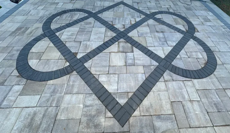 Paver patio with a decorative dark paver inlay pattern set into the stone